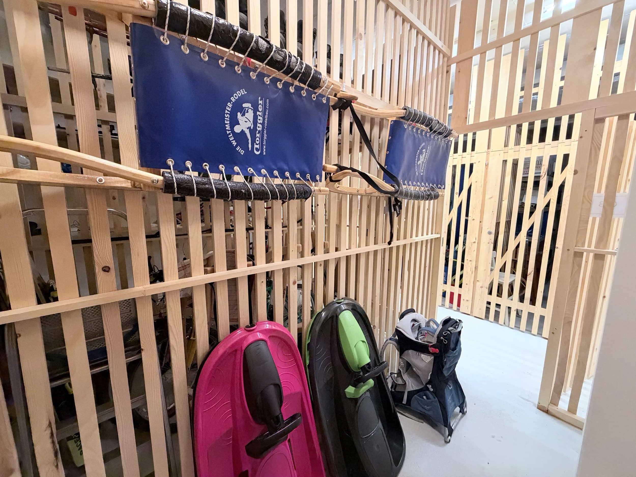 Kellerabteil mit zwei Davoser Schlitten an der Lattenwand, zwei Bobs und der Kindertrage