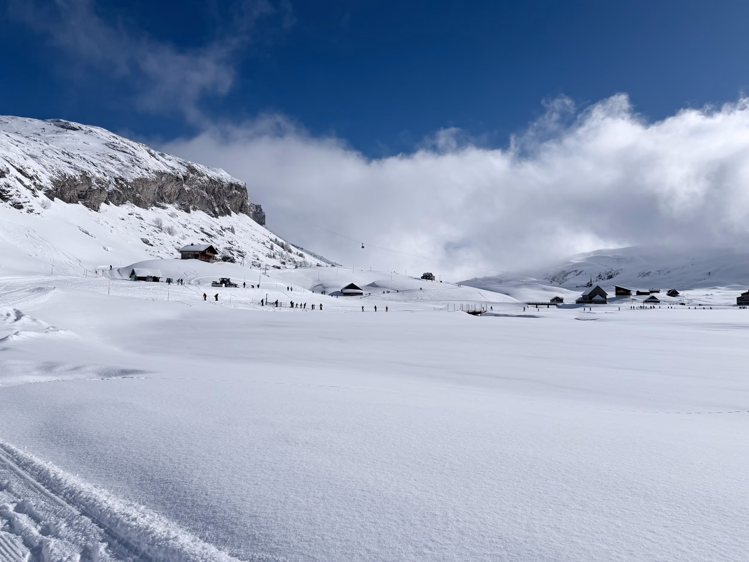 Der verschneite Melchsee mit Schlepplift und Alphütten unter blauem Himmel