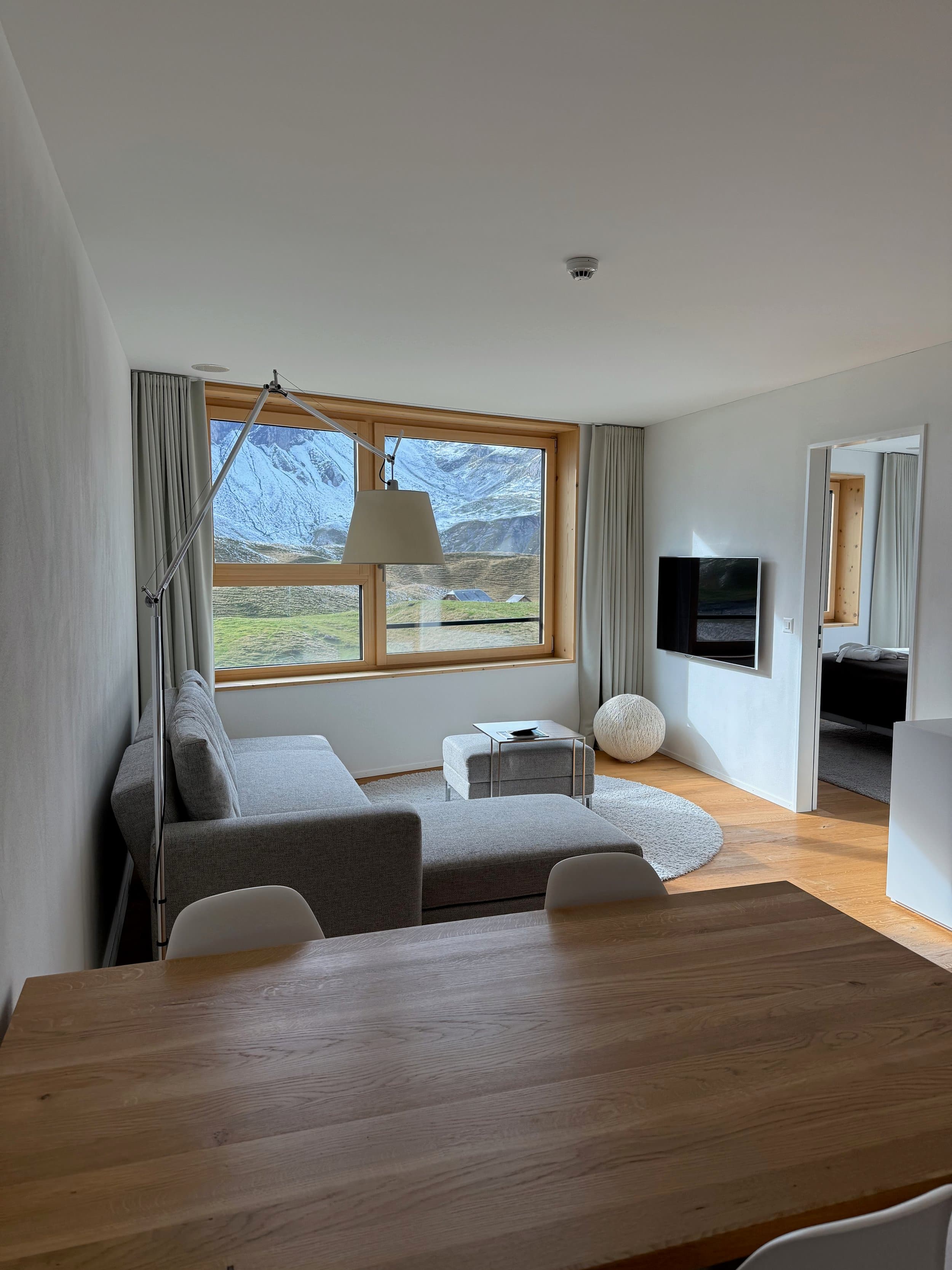 Ecksofa und Esstisch vor dem grossen Holzfenster