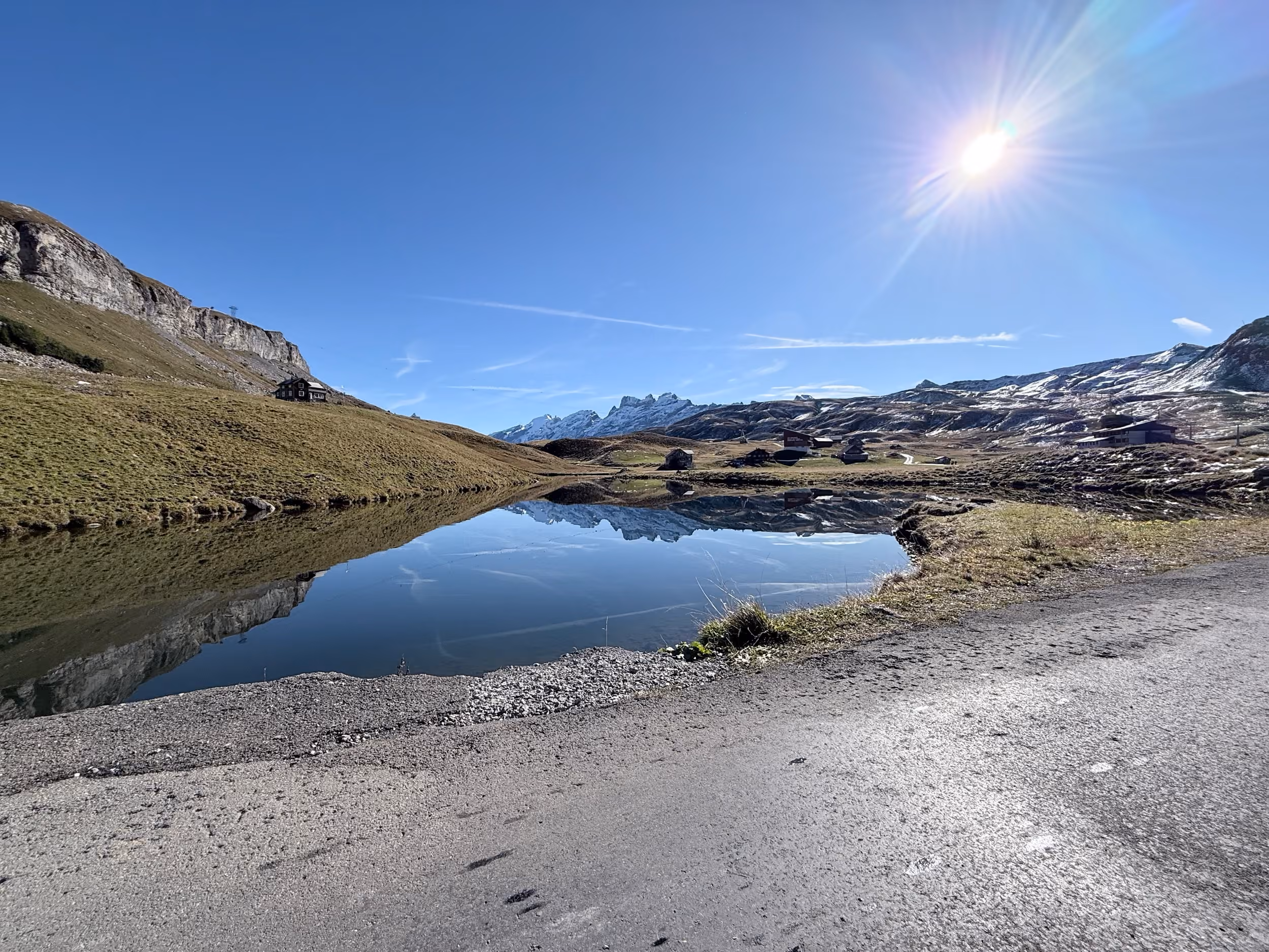 Kleiner Bergsee mit Spiegelung, dahinter die Gondelbahn-Station Bonistock und verschneite Gipfel