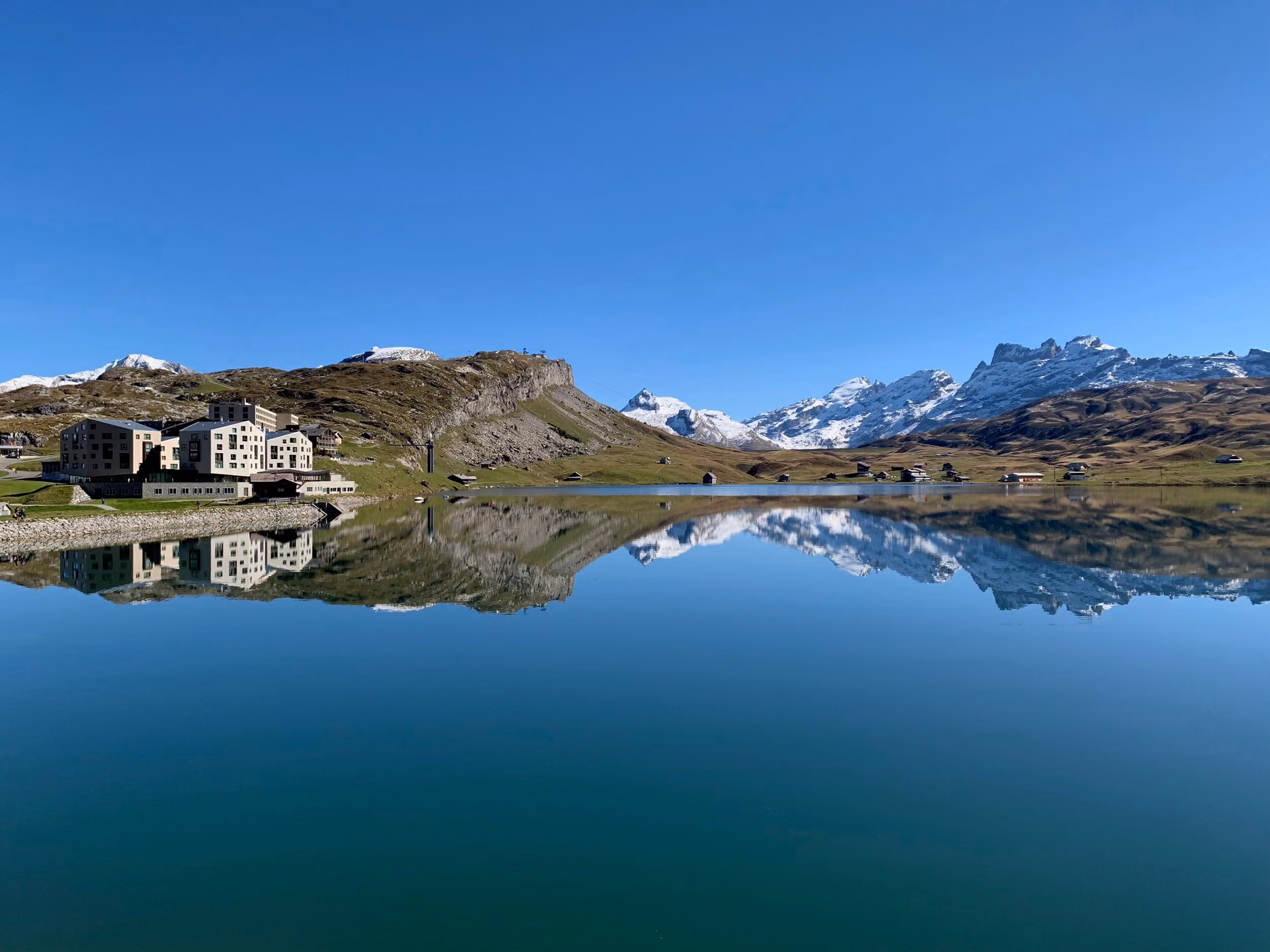 Die Frutt Lodge und die Berge spiegeln sich im ruhigen Melchsee